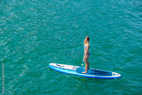 SUP Stand up paddle board. Blond girl sailing on paddle board in sea. Aerial view. Woman on summer holidays vacation lifestyle. Mtsvane Kontskhi Beach, Batumi, Georgia. © Khrystyna Bohush