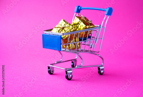 trolley with Christmas gifts on a pink background