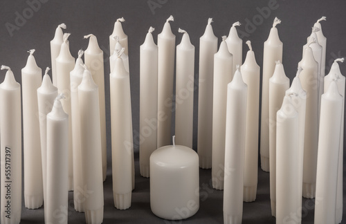 Unlit white candles on a gray background, copy space.