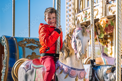 Cheerful boy riding merry go round