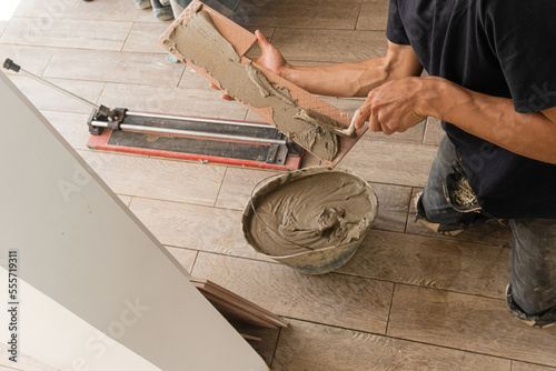 Crop repairman applying cement on tile board photo