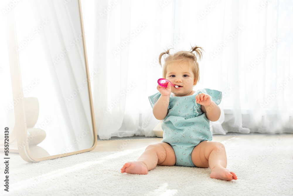 Cute baby girl playing with first toothbrush in domestic room. Copy space for advertisement Cute baby girl playing with first toothbrush in domestic room. Copy space for advertisement