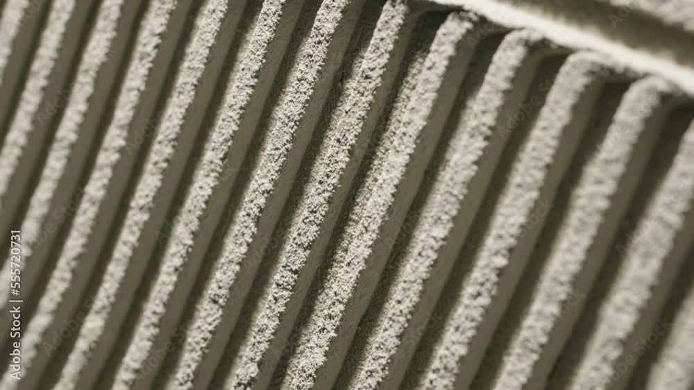 Gray wall glue plaster comb surface prepared for tiling. Tile adhesive notched trowel patterns. Texture background of tile mortar paste. Grey cement wall with a linear pattern. Macro shot. Gray wall glue plaster comb surface prepared for tiling. Tile adhesive notched trowel patterns. Texture background of tile mortar paste. Grey cement wall with a linear pattern. Macro shot.