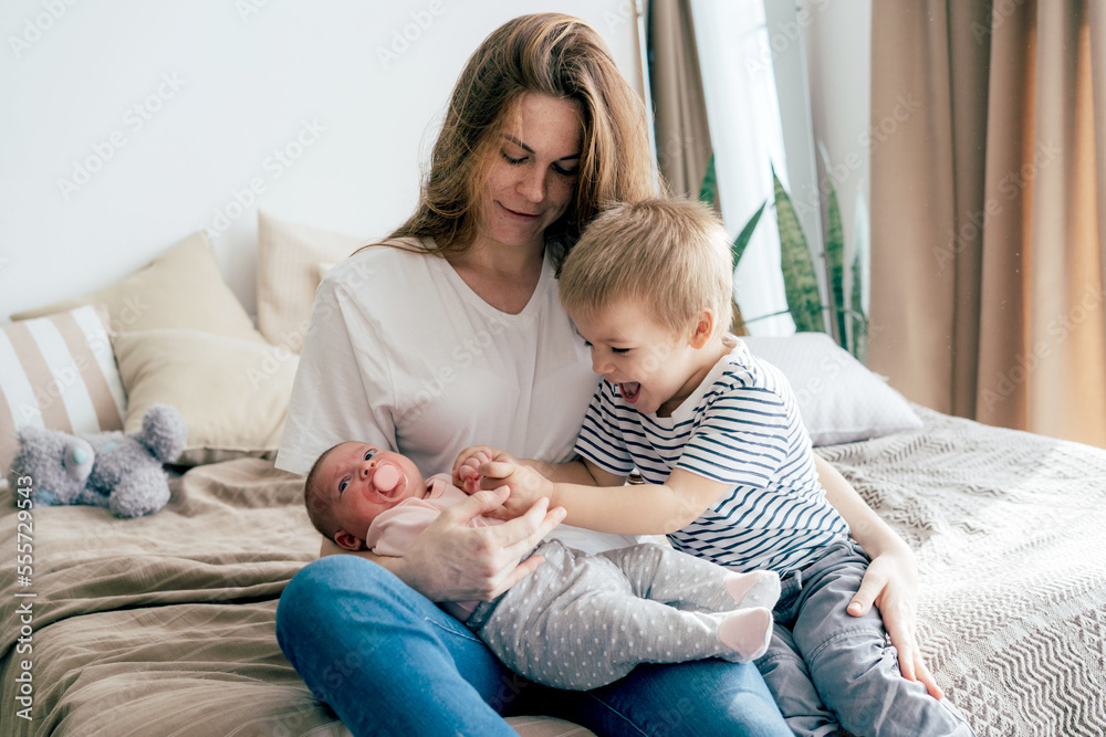 Young mother with children at home. Newborn sister and brother toddler with parent. Young mother with children at home. Newborn sister and brother toddler with parent.
