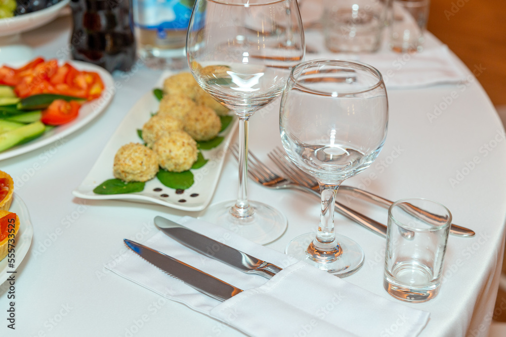 Fototapeta premium Served for holiday banquet restaurant table with dishes, snack, cutlery, wine and water glasses.