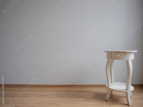 Mesa de madera blanca aislada en un fondo gris claro con piso de madera, aislado, minimalista photo