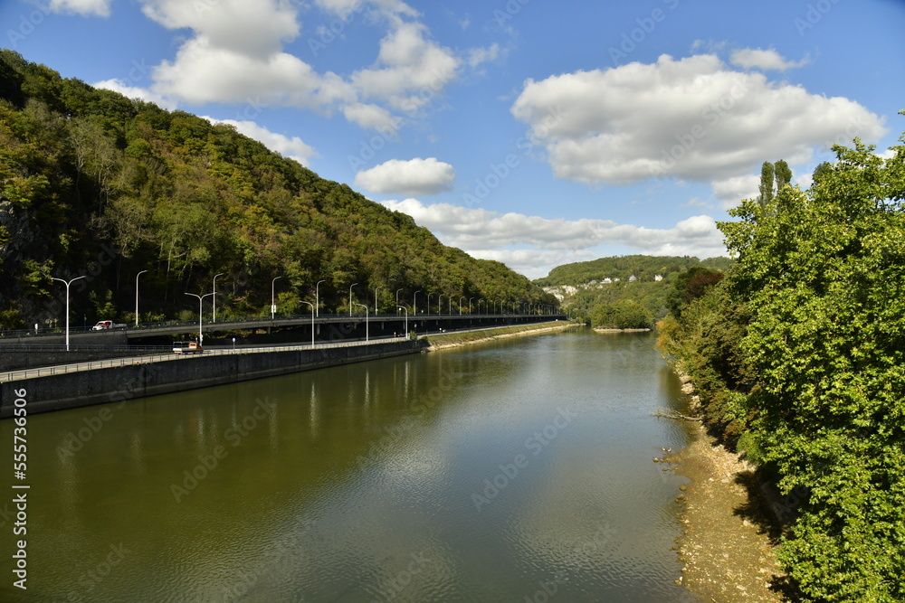 La Meuse avec voie de circulation routière entre les hautes collines boisées à Lustin au sud de Namur