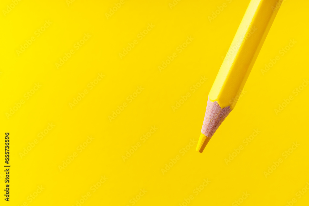Fototapeta premium Colored pencil close-up with selective focus on the stylus and a blurred yellow background. Copy space