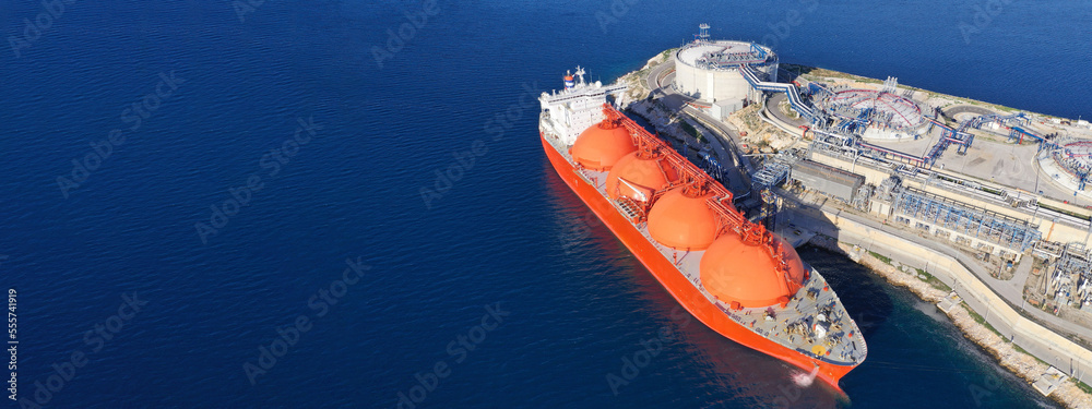 Aerial drone ultra wide panoramic photo of LNG (Liquified Natural Gas) tanker anchored in small gas terminal island with tanks for storage