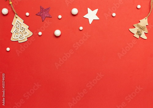 Christmas red background with copy space, stars and snowflakes. Beautiful holiday card, wooden Christmas trees on a red background, white and purple star, white round snowflakes