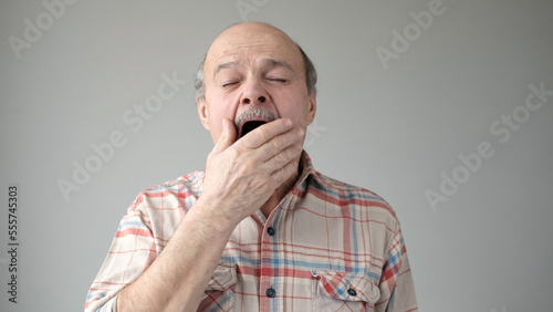 Obraz na plátne sleepy senior hispanic man yawning being tired.