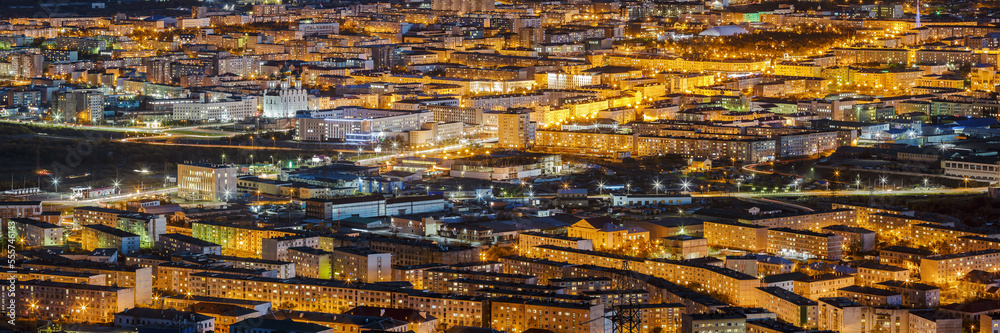 Beautiful night view from the top of the illuminated streets and buildings. Panorama of the night city. Aerial panoramic view of residential areas and the Cathedral. Magadan, Magadan Region, Russia.
