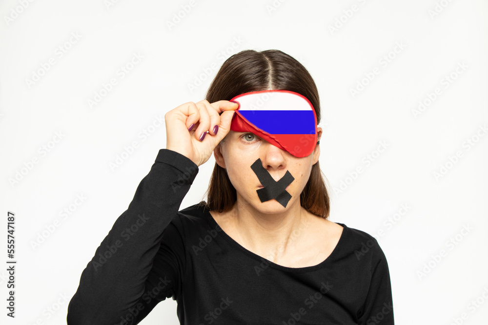 A girl with a blindfold in the color of the flag of Russia and a band-aid closed her mouth on a white background, a Russian girl does not see or hear, a deaf and dumb A girl with a blindfold in the color of the flag of Russia and a band-aid closed her mouth on a white background, a Russian girl does not see or hear, a deaf and dumb