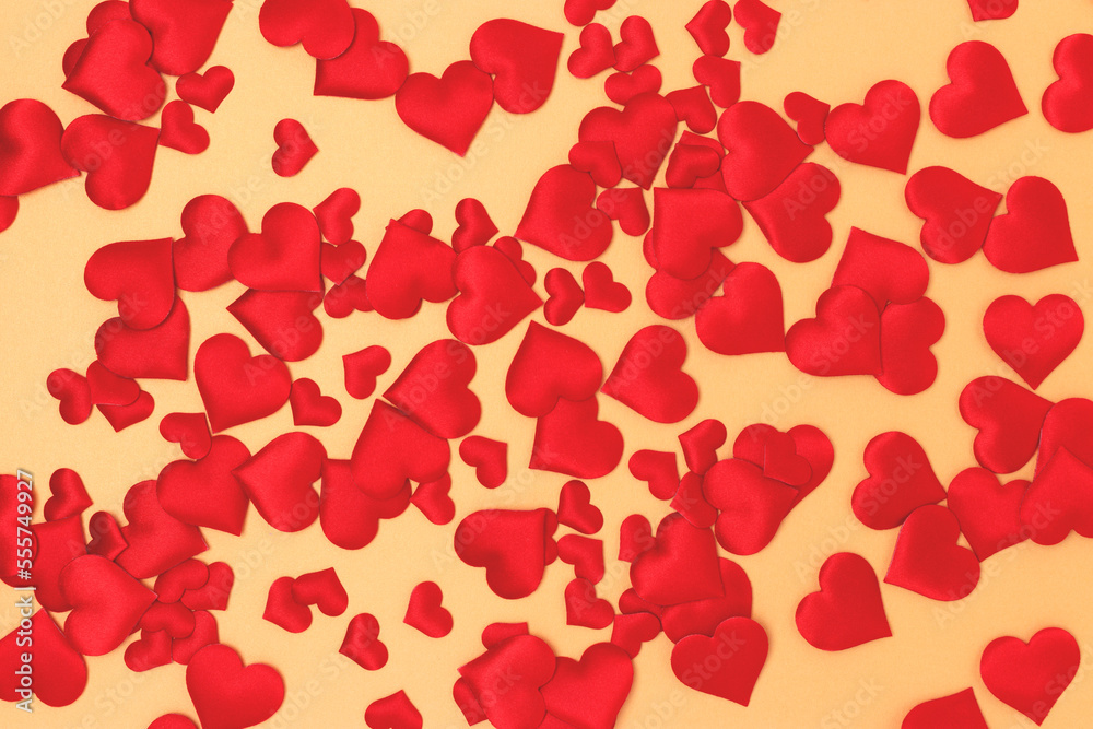 Texture made of textile red confetti in a heart shape on a gold colored background.