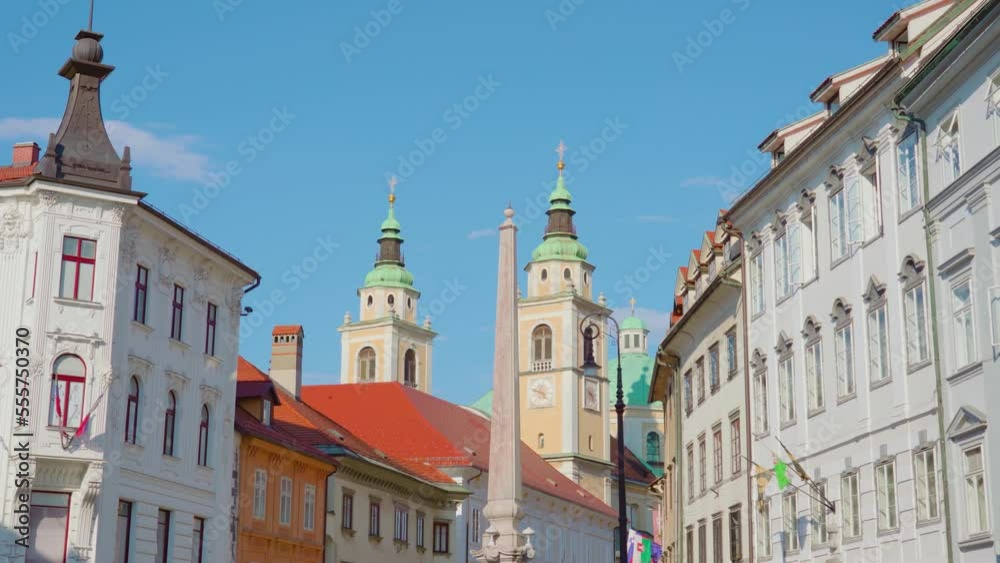 Street of capital of Slovenia Ljubljana with historical buildings and multi-colored slightly elongated roofs under blue sky Street of capital of Slovenia Ljubljana with historical buildings and multi-colored slightly elongated roofs under blue sky