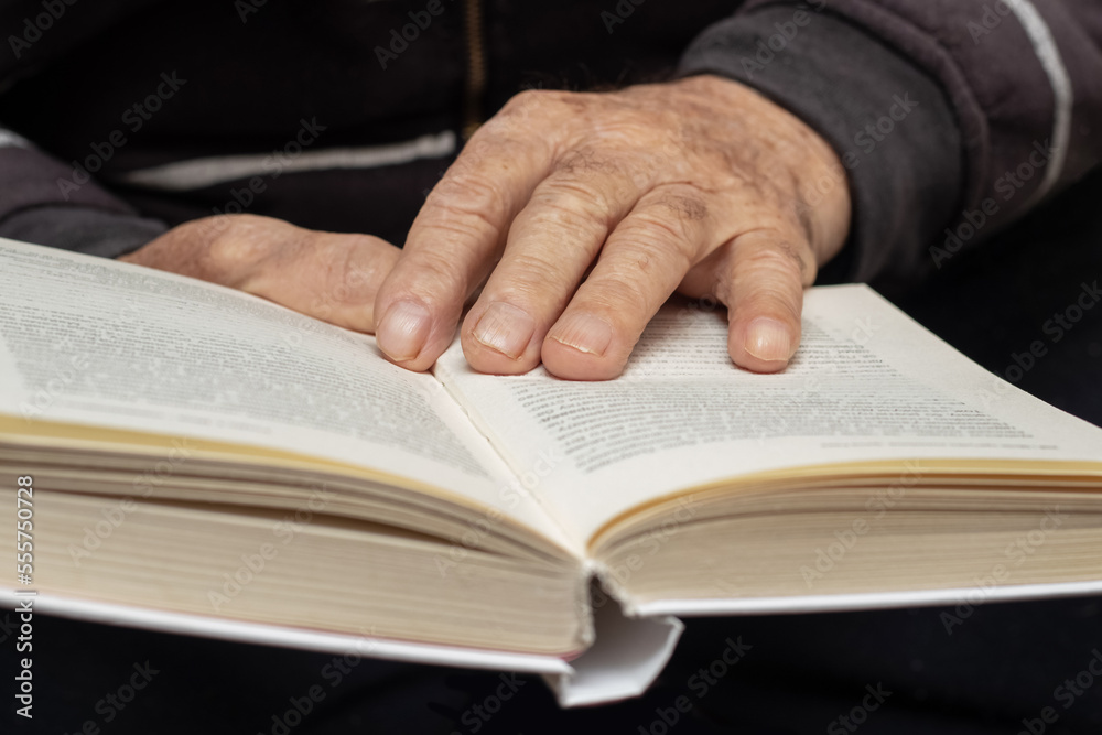 An elderly man, a grandfather, holds an open book in his hands. Leisure for the elderly. Reading a book An elderly man, a grandfather, holds an open book in his hands. Leisure for the elderly. Reading a book