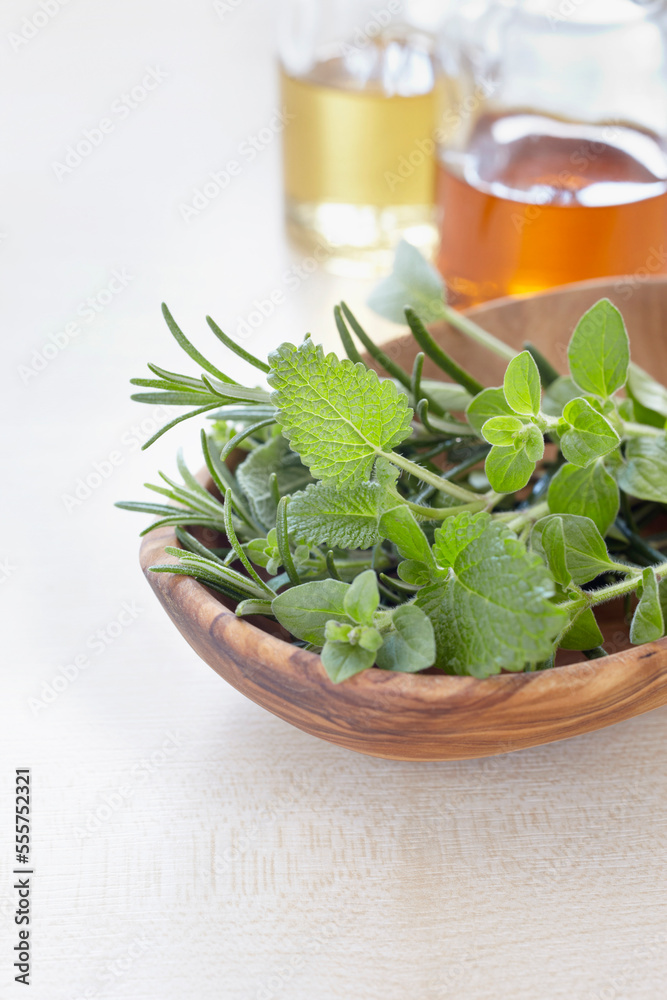 Fresh herbs in a bowl and bottles of oil for aromatherapy Fresh herbs in a bowl and bottles of oil for aromatherapy