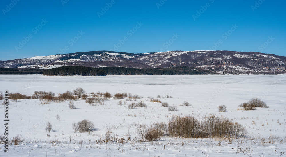 Winter landscape by the frozen lake with hills in the background background. Frozen Lake on a cold winter day Winter landscape by the frozen lake with hills in the background background. Frozen Lake on a cold winter day