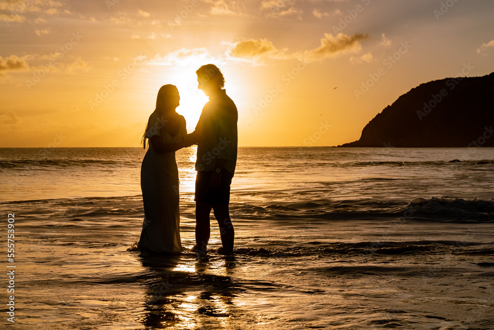 Silhouette of romantic young couple looking at each other during the sunset on a tropical island beach