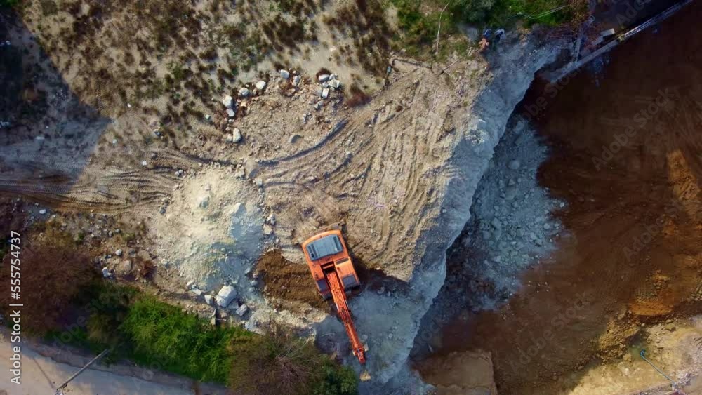 the excavator works on the land plot, levels the ground for the foundation, shooting from the air.