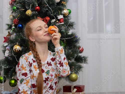 a beautiful girl with long hair, in a home interior, posing in front of New Year decorations, a Christmas tree and gifts.