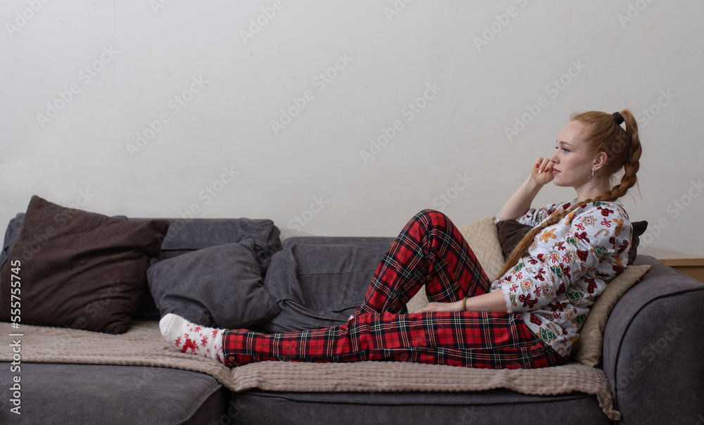 Obraz premium beautiful girl posing on the couch, at home, with a book and a remote control
