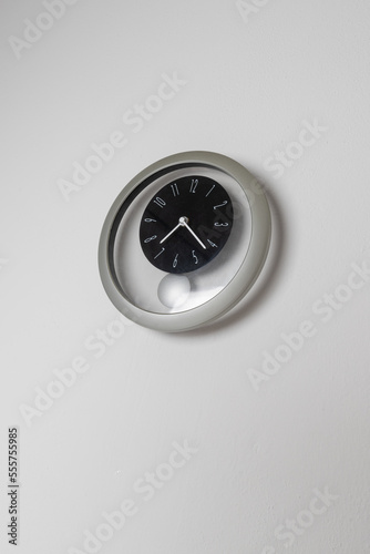 Round clock with a pendulum on a white background.