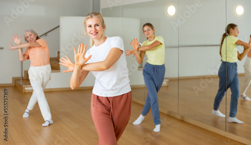 Young girl with her mother and grandmother dancing aerobics at lesson in the modern dance class