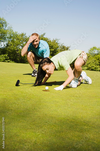 Golfer Trying to Blow Golf Ball Into Hole photo