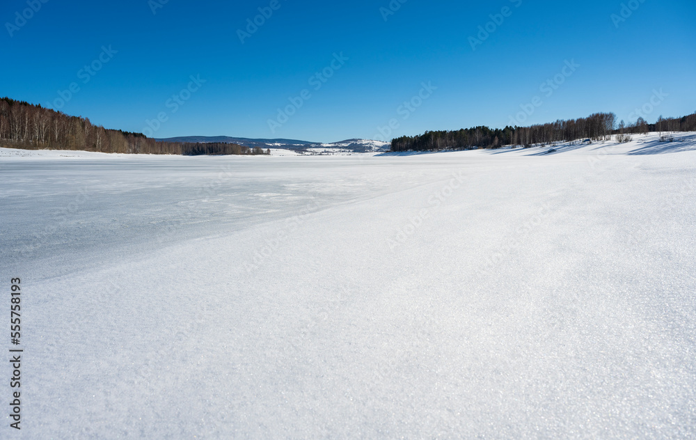 Winter landscape by the frozen lake with hills in the background background. Frozen Lake on a cold winter day