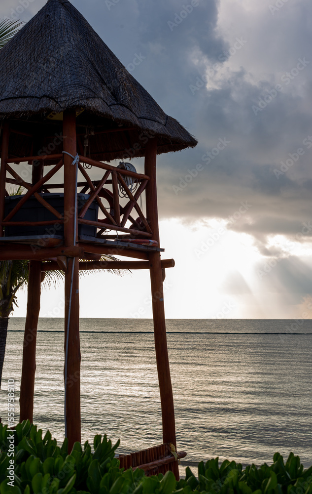 cabane au toit de paille en hauteur sur le bord de la plage lors d'un matin au ciel ennuagé avec vue sur la mer