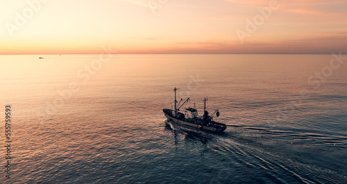 Fotografia Fishing boat catching fish at sunset aerial view from drone