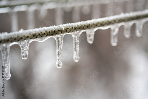 Electric cables, wires are covered with ice after the phenomenon of freezing rain. Selective focus 
