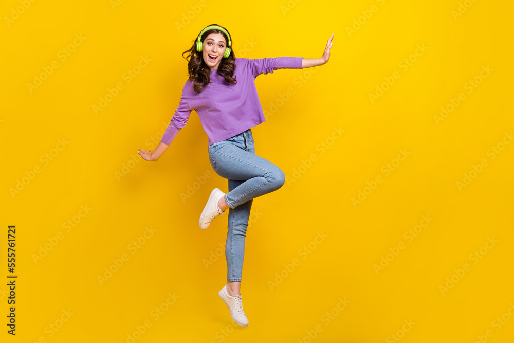 Full body portrait of active satisfied lady jumping enjoy new playlist isolated on yellow color background Full body portrait of active satisfied lady jumping enjoy new playlist isolated on yellow color background