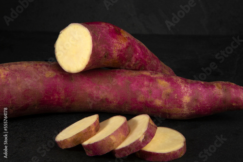 Portion of sweet potato, whole and sliced, over black background photo