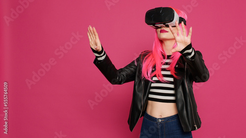 Modern stylish girl using vr glasses with augmented reality tech, futuristic interactive wireless headset. Young pretty adult having fun with simulator and 3d innovation, electronic system.