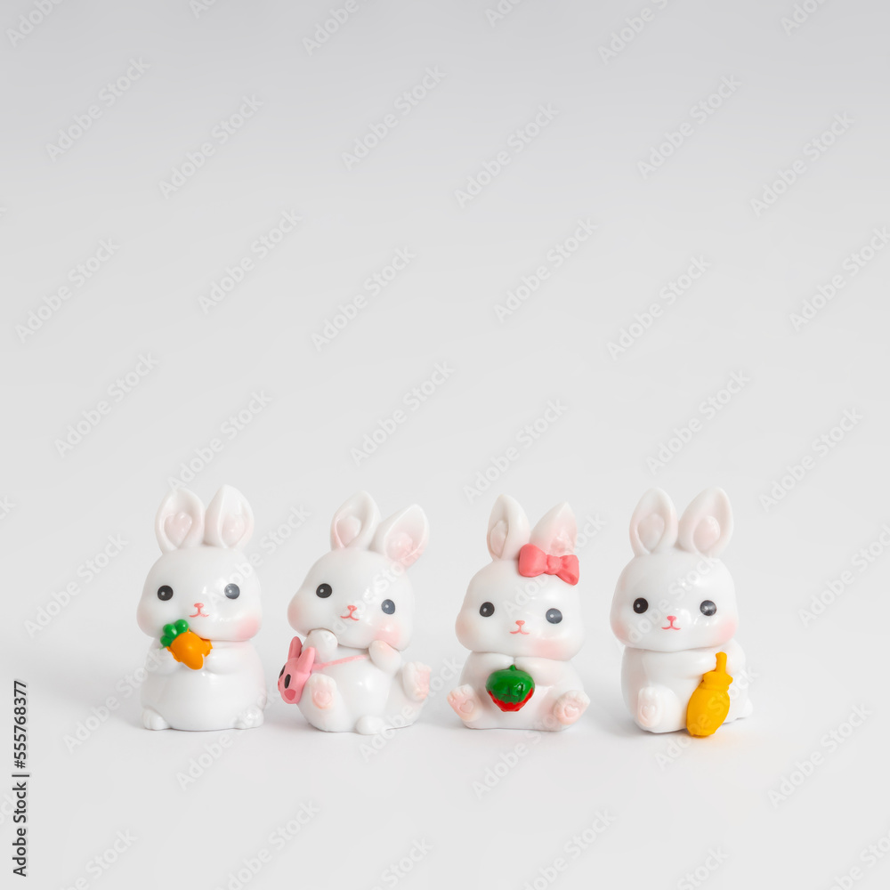 Fototapeta premium Little white rabbits on a white background. Creative greeting card design in a minimalist style. Chinese Lunar New Year composition for 2023. Year of the Rabbit.