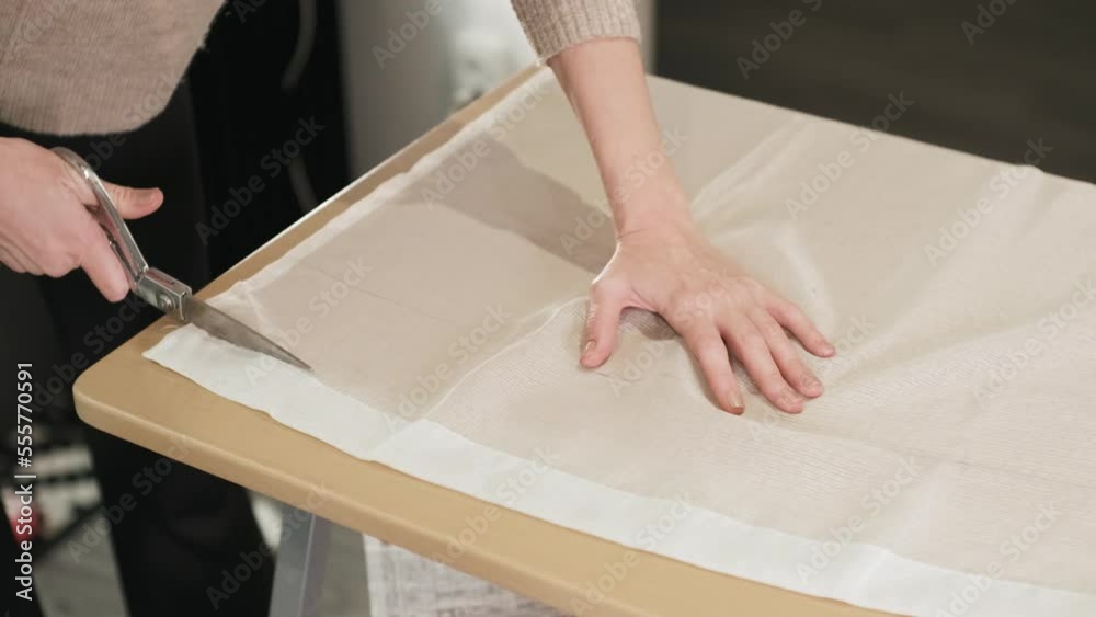 A woman holding big scissors in her hands and cuts a white fabric close up A woman holding big scissors in her hands and cuts a white fabric close up