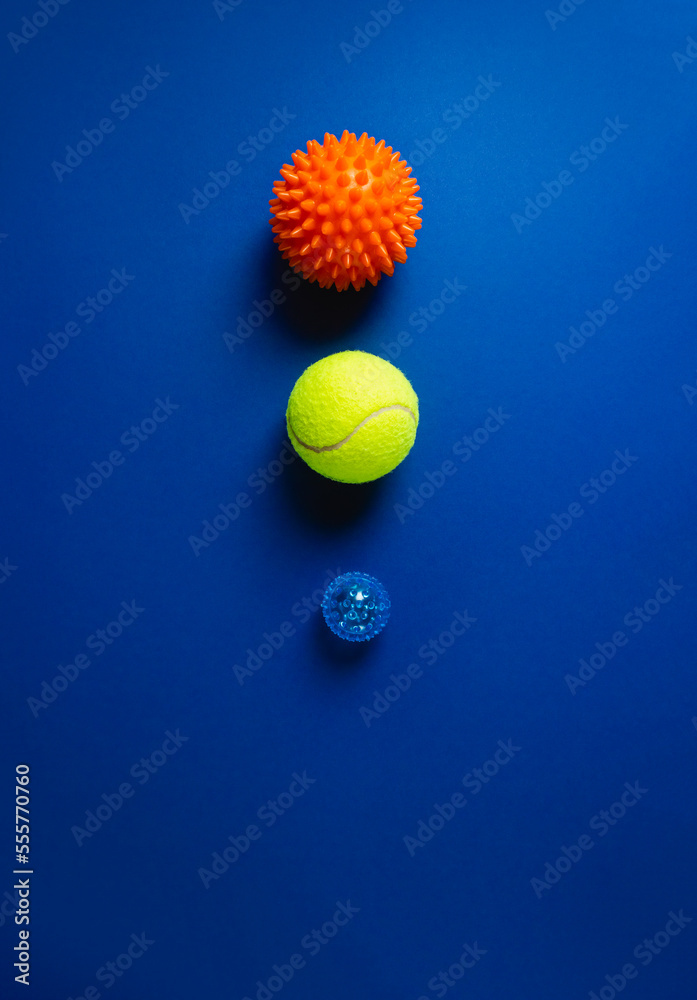 Three myofascial release balls for trigger points on dark blue background. Equipment for MFR, self massage and physiotherapy. Reflexology therapy concept. Vertical banner, selective focus