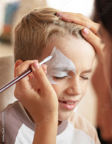 Master making aqua makeup on boys face. face painting kids. Child animator, artist's hand draw face painting. High quality photo