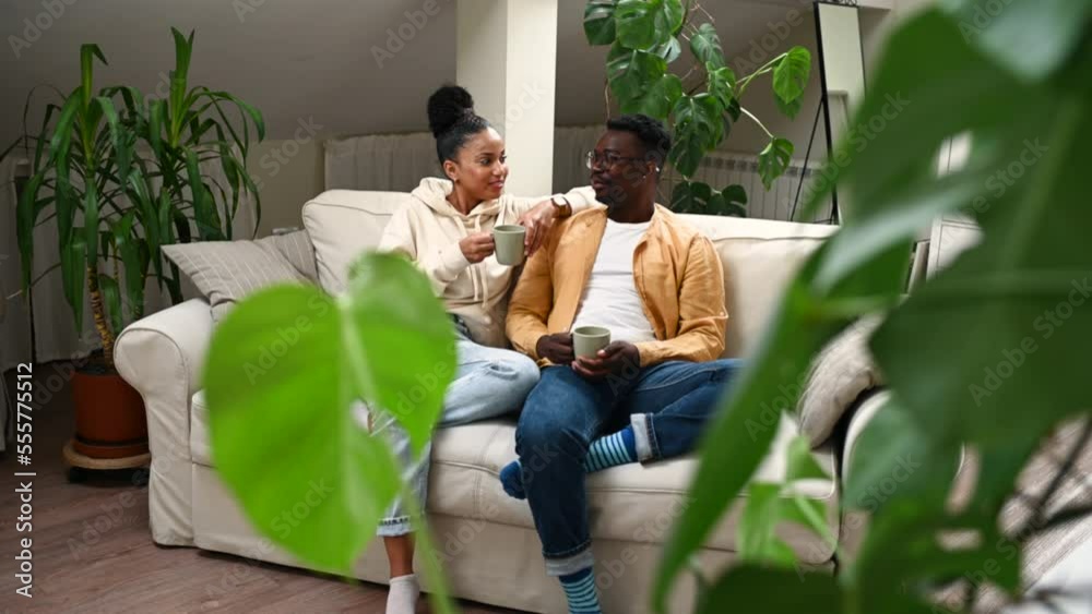 Diverse couple relaxing on cozy sofa at home and drinking coffee Diverse couple relaxing on cozy sofa at home and drinking coffee