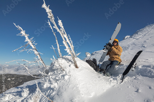 A rider with a splitboard in a ski helmet on the background of a snowy mountain