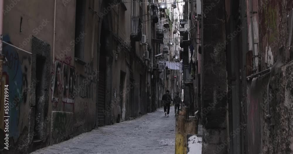 Two guys are walking along a colorful narrow street in the historical part of Naples Italy Two guys are walking along a colorful narrow street in the historical part of Naples Italy