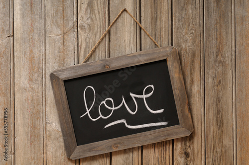 Love Written in Cursive on Chalkboard and Hanging on Wooden Wall