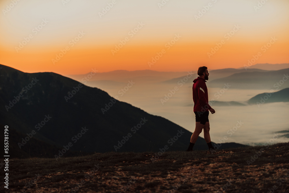 An athlete rests on top of a mountain after exhausting running training