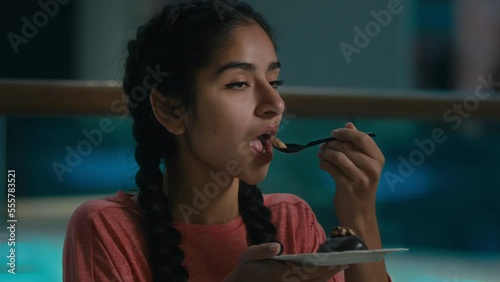 Arabian young woman client eat musty chocolate cake with teaspoon distasteful spoiled brownie in cafe bad unhealthy product tasteless food high calorie dessert disgust reaction unpleasant taste gmo