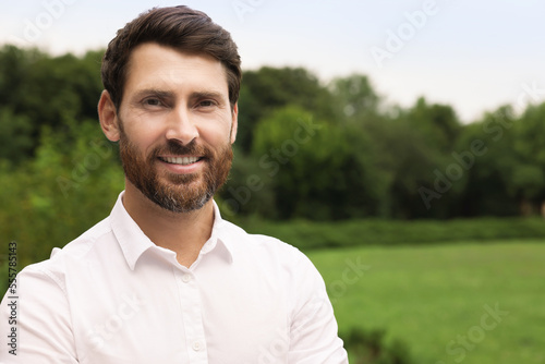 Portrait of handsome bearded man in park, space for text