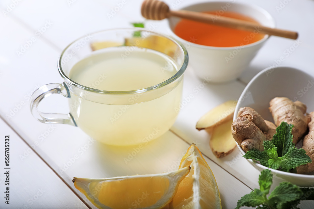 Delicious ginger tea and ingredients on white wooden table Delicious ginger tea and ingredients on white wooden table