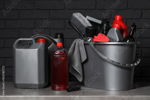 Different car cleaning products on grey table near black brick wall photo