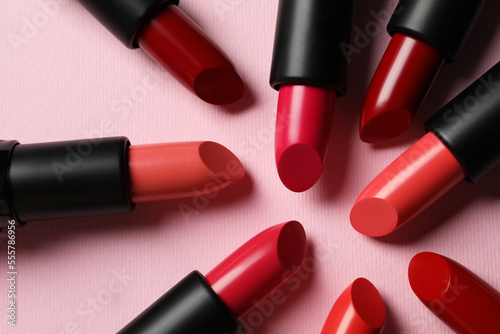 Many bright lipsticks on pink background  flat lay